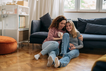 mother and daughter hugging , sits in living room