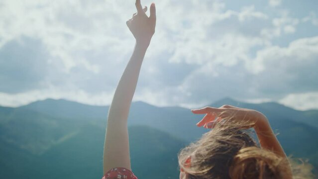 Girl enjoy sunlight raising hands to cloudy sky closeup. Back view woman outdoor