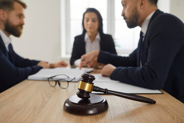 Closeup focus on gavel in lawyer office. Partners or professional and client talk on court or...