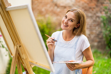 Woman enjoys woman painting on canvas outdoor.