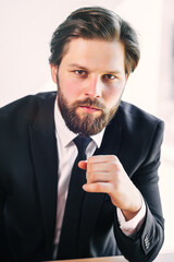 Businessman posing confidently at professional office workplace. Dressed in a classic suit with a tie.