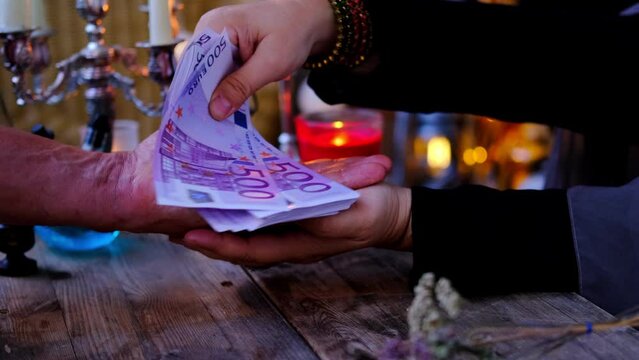 Librate with money over male client's hand, healing or oracle foretelling, candles, Female Fortuneteller or esoteric Oracle performs spell, removes damage, esoteric business, magic to increase income