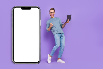 Photo of confident lucky guy wear grey shirt reading modern device empty space rising fist isolated violet color background