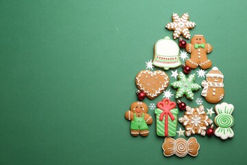 Christmas tree shape made of delicious gingerbread cookies on green background, flat lay. Space for text