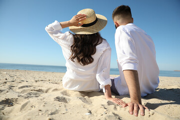 Young couple on beach near sea, back view. Honeymoon trip