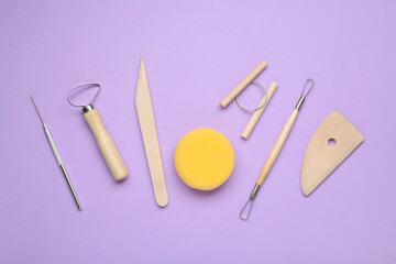 Set of clay modeling tools on violet background, flat lay