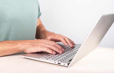 Fototapeta na wymiar Man hands closeup typing on laptop keyboard. Using computer for work, study. Freelancer lifestyle. Male sitting at desk