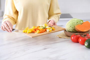 Obraz na płótnie Canvas Woman holding cutting board with mix of fresh vegetables in kitchen, closeup