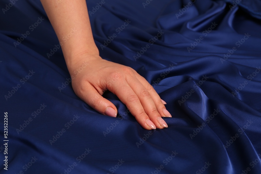 Wall mural Woman touching silky blue fabric, closeup view