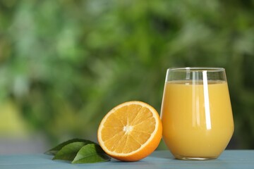 Delicious orange juice and fresh fruit on light blue wooden table against blurred background. Space for text