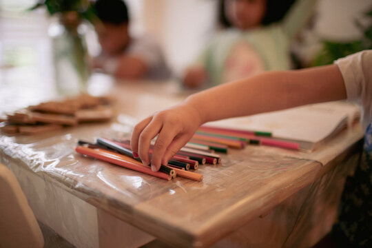 Girl reaching for colored pencil on table