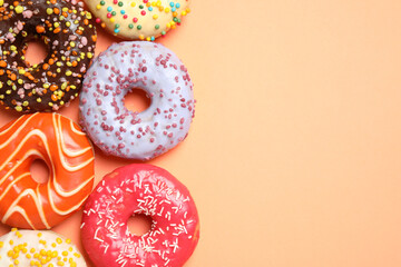 Delicious glazed donuts on orange background, flat lay. Space for text