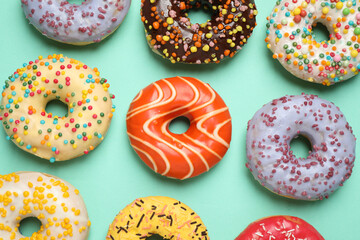 Delicious glazed donuts on turquoise background, flat lay