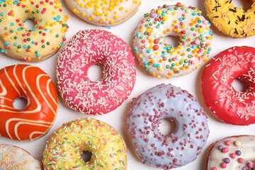 Delicious glazed donuts on white background, flat lay