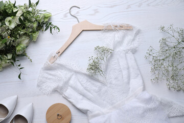 Fototapeta na wymiar Beautiful wedding dress, engagement ring and flowers on white wooden background, flat lay