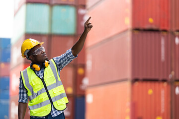 Black African engineer man worker working in container port terminal. Attractive foreman worker processes orders and product at warehouse logistic in cargo freight ship for import and export in harbor