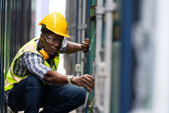 Black African engineer man worker working in container port terminal. Attractive foreman worker processes orders and product at warehouse logistic in cargo freight ship for import and export in harbor