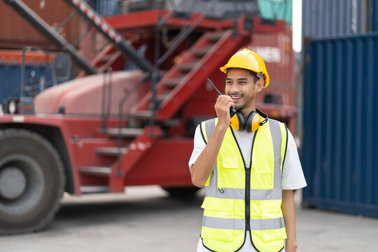 Asian handsome young man worker working in container port terminal. Attractive male engineer people process orders and product at warehouse logistic in cargo freight ship for import export in harbor.