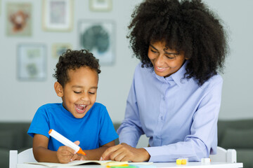 Portrait of cute african boy in using laptop with teacher, learning