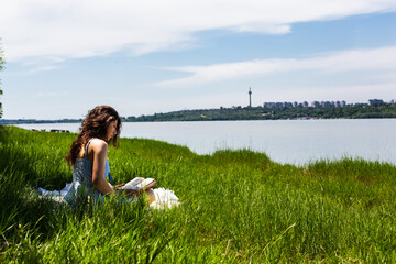 Woman sitting on the grass with a book