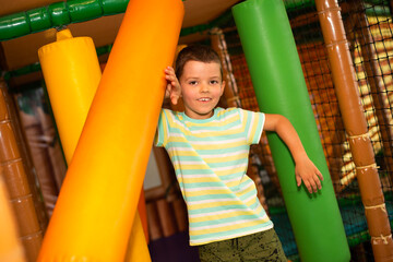 A cute cheerful child on a colorful obstacle course in a children's play center.