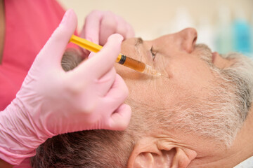 Woman hands of beautician injecting beauty injection into cheek