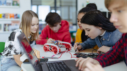 Group of high school students building and programming electric toys and robots at robotics classroom