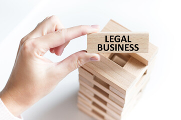 LEGAL BUSINESS text on a wooden bar in the hands of a girl on a light background