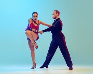 Obraz premium Beautiful woman and man, professional dancers dancing ballroom dance isolated on blue background. Concept of art, beauty, music, style.
