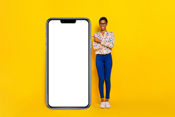 Full body portrait of positive person direct finger empty space large phone isolated on yellow color background