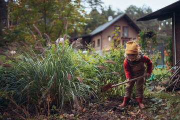 Litlle girl taking care of vegetable garden, spading soil.