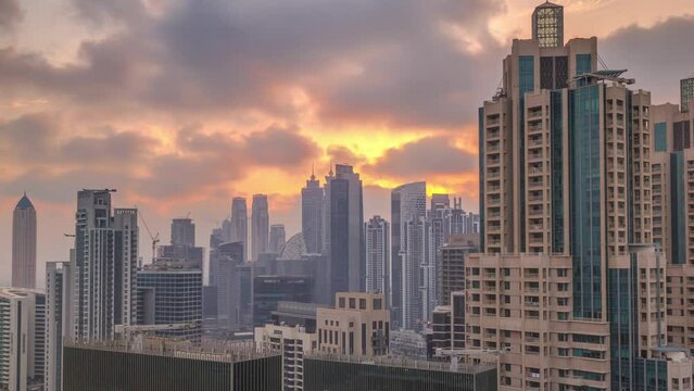Dubai skyscrapers with golden sunset over business bay district timelapse. Aerial view from of downtown in United Arab Emirates. Colorful clouds and sun beams