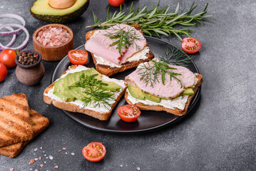 Fresh, delicious ham, butter, avocado and sesame seeds sandwiches on a wooden cutting board