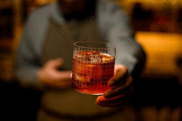 Selective focus on glass with grid pattern full of cold cocktail in male hand