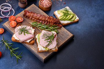 Fresh, delicious ham, butter, avocado and sesame seeds sandwiches on a wooden cutting board