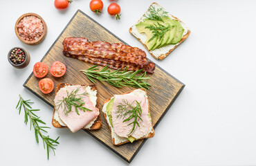 Fresh, delicious ham, butter, avocado and sesame seeds sandwiches on a wooden cutting board