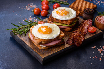 Fresh, delicious sandwiches with fried egg, ham, butter, avocado and sesame seeds