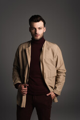 Obraz premium Stylish brunette man in jacket posing isolated on grey.