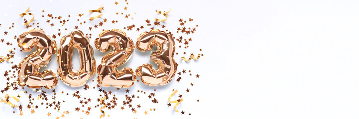 Banner with 2023 gold foil balloons, stars confetti and ribbons on a blue background. Holidays concept with place for text.