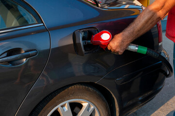 Mature man pouring petrol into tank of his vehicle on filling station. Travel,transportation and...