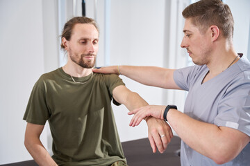 Military doctor helps a soldier develop a wounded arm