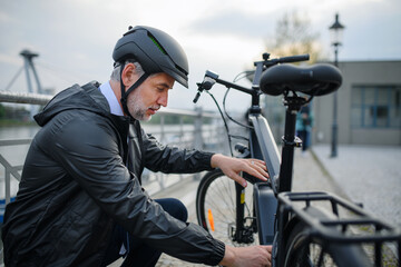 Portrait of businessman in bicycle helmet fixing his bike, sustainable lifestyle concept.