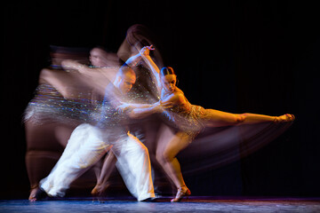 Energy in movements. Two professional dancers dancing ballroom dance isolated on dark background...