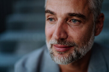 Close-up portrait of handsome businessman sitting out, looking at camera.