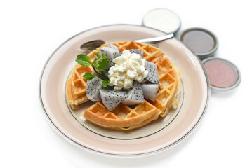 Belgium waffles with sliced dragon and ice cream on a plate with chocolate toping and fruit sauce