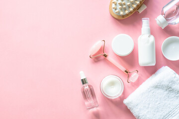 Obraz na płótnie Canvas Natural cosmetics on pink. Skin care product, cream, soap serum, jade roller and white towel. Flat lay image with copy space.