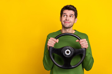 Photo of funny dreamy young guy dressed green pullover holding steering wheel looking empty space...