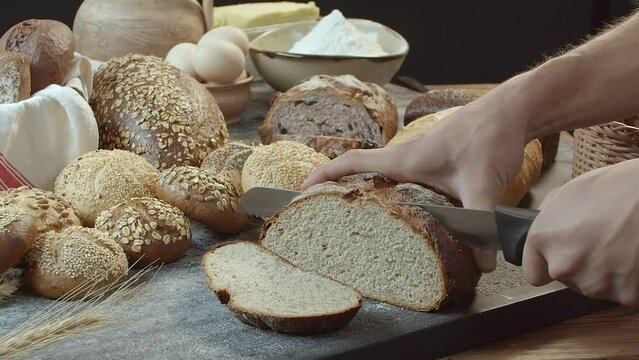 Hands cutting the baked Dutch bread on the table