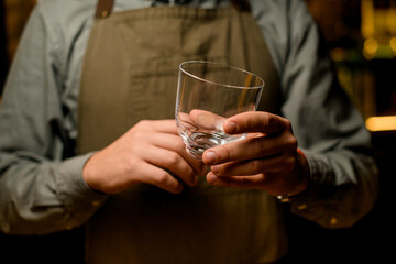 close-up view of caucasian male hand holding clean transparent empty glass for cocktail