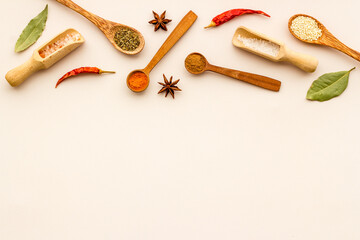 Variety of colorful spices and herbs in wooden spoons on kitchen table, top view